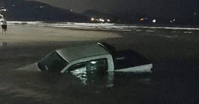Mulher tenta atravessar rio com picape e abandona veículo naufragado.